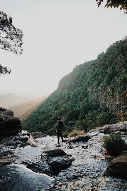Man near a creek flowing down a mountain, enjoying nature while traveling full-time in an RV.

