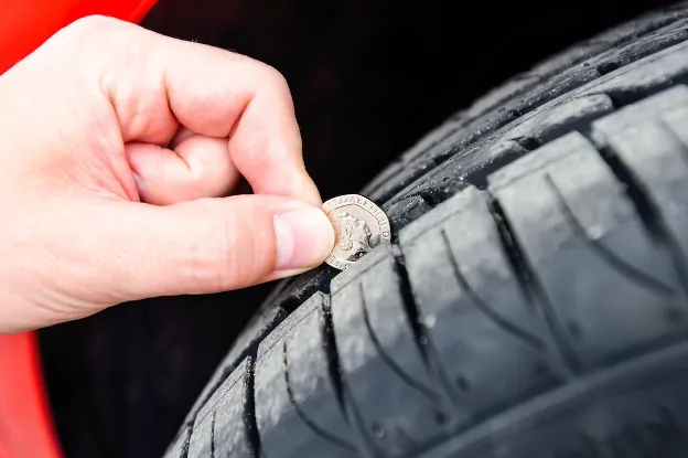  A small coin inserted into a tire tread to check depth—part of inspecting and inflating RV tires before hitting the road.