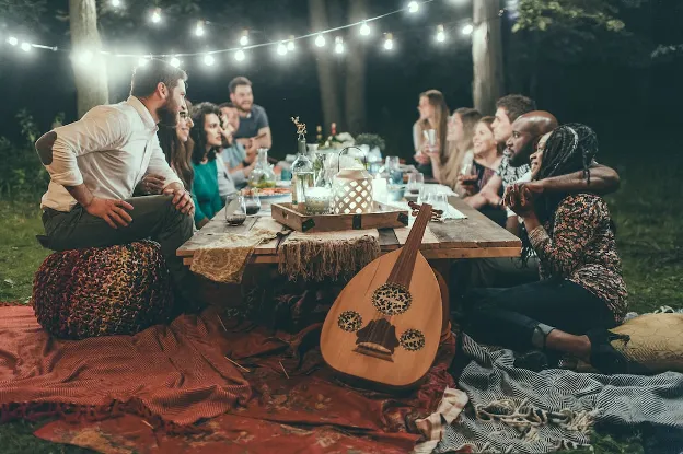 Group of people enjoying food and conversation around a table in the woods, highlighting the community aspect of RV living.

