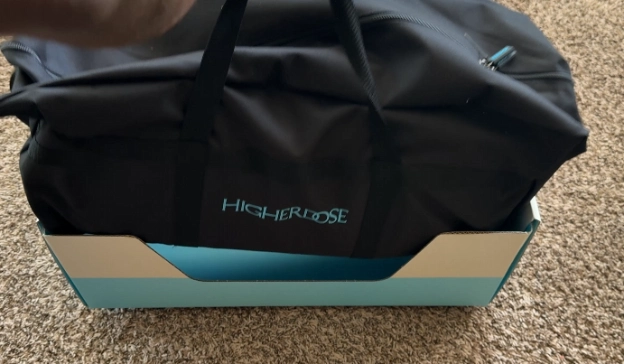 HigherDose infrared sauna blanket folded inside branded black carry bag for storage and portability.