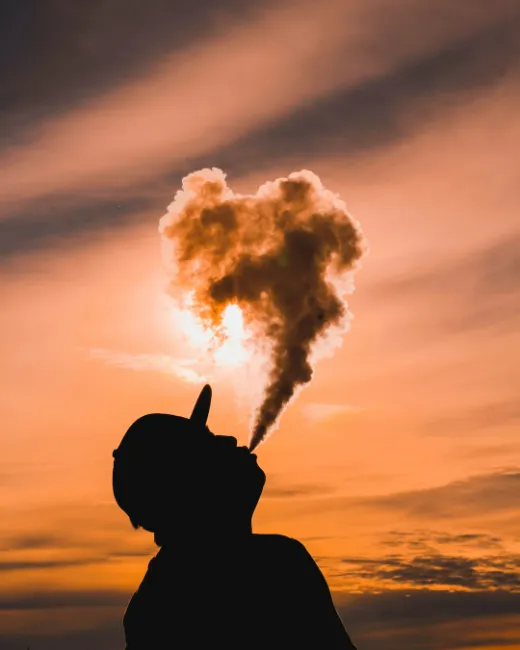 guy vaping in front of the sun set