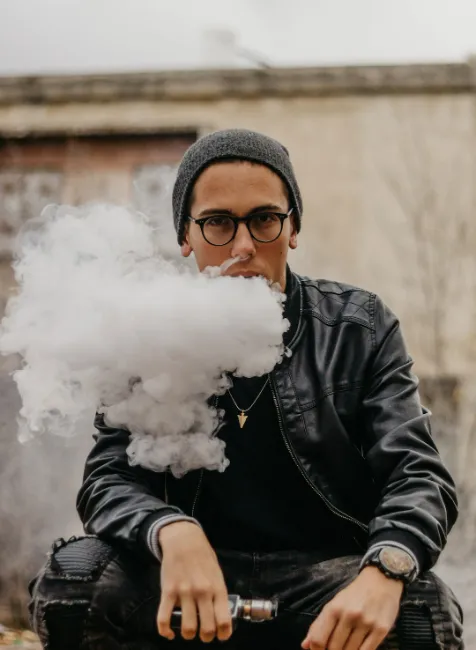 guy in the street vaping seating on the bench