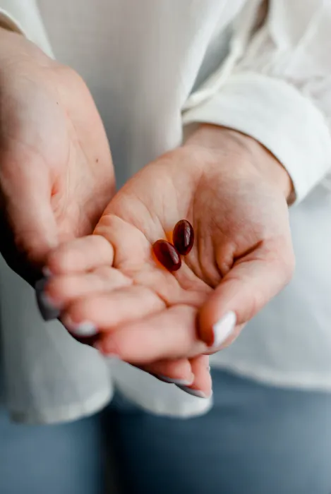 outstretched hand holding two gelcap supplements