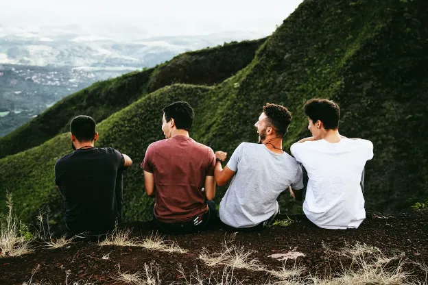 four men sitting at the edge of hills