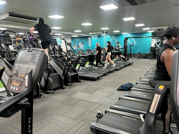 Inside Pure Gym showing cross trainers, treadmills and gym floor equipment