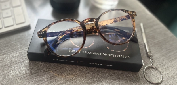 Blue light blocking glasses on desk beside keyboard in home office setup