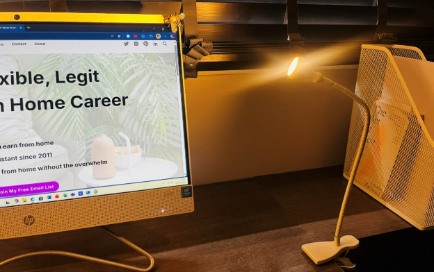 Clip-on desk lamp glowing beside computer screen in home office workspace