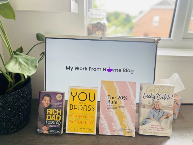 Four recommended money books for Virtual Assistants on a desk in a home office
