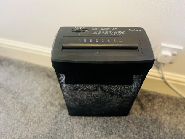Black paper shredder placed on carpeted floor beside home office desk