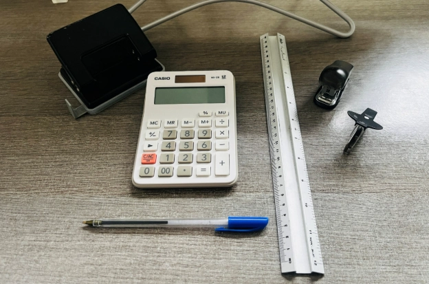 Calculator, ruler, stapler and pen neatly arranged on home office desk