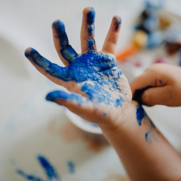 Child with paint-covered hands enjoying messy summer holiday arts and crafts for kids at home