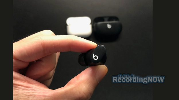 Holding Beats Studio Buds wireless earbud with AirPods Pro 2nd generation in background