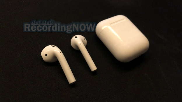 AirPods 2 earbuds sitting next to lightning charging case on desk