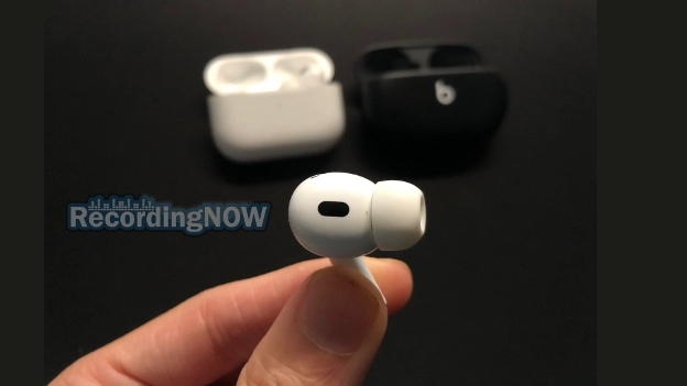 Holding Apple AirPods Pro 2 earbud with Beats Studio Buds in background