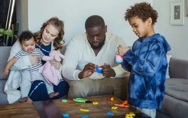 multiethnic family playing toys together around table