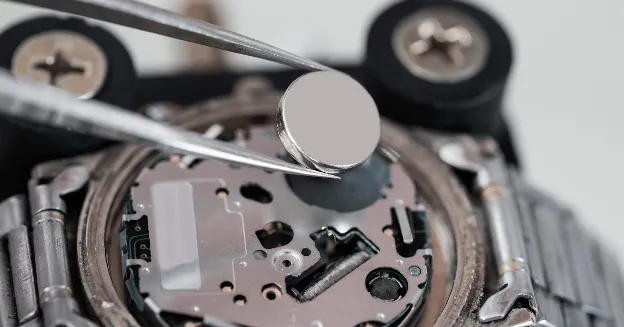 Picture of a quartz battery being placed inside a watch