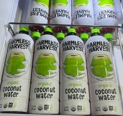 Fridge stocked with Organic Harmless Harvest Coconut Water bottles, healthy summer beach essentials.